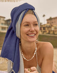 La Luna Turkish towel in Indigo – head wrapped while laying on sand at the beach
