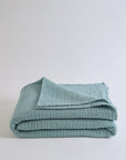 Summer Blanket in Sage – Folded blanket with label visible and soft sage color fabric