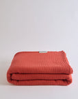 Summer Blanket in Terra – Folded terracotta-toned blanket with subtle gauze weave