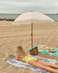 Pale Pluie Turkish towel in Mellow Indigo – lifestyle beach scene with model lying face down