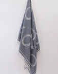 Gray towel with circular patterns hanging against a white wall