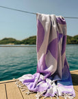 Fiori Turkish towel in Lilac – hanging on dockside rope overlooking a calm bay