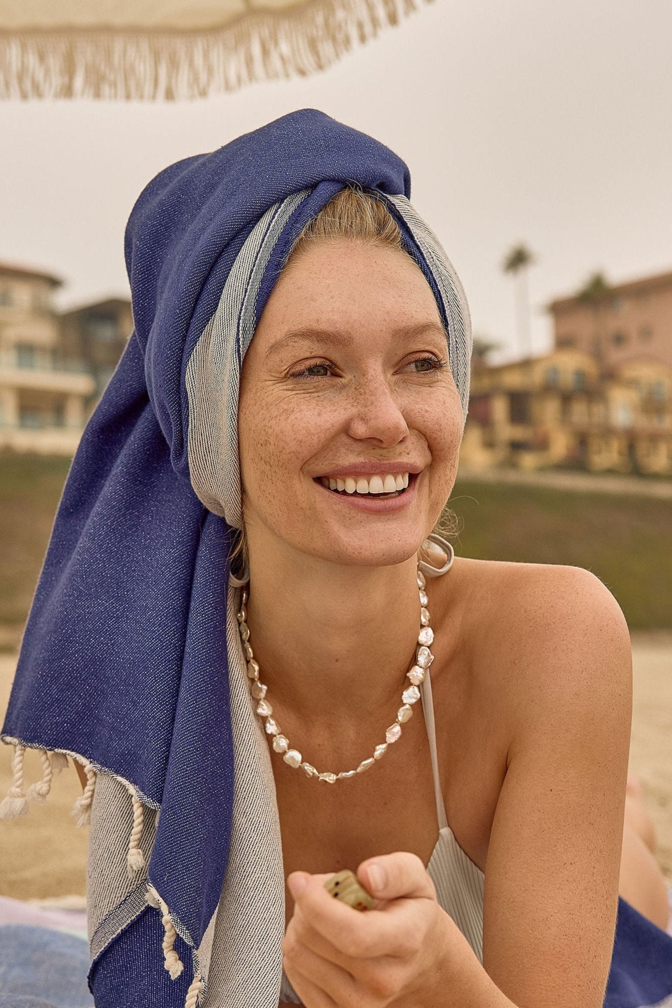 La Luna Turkish towel in Indigo – head wrapped while laying on sand at the beach