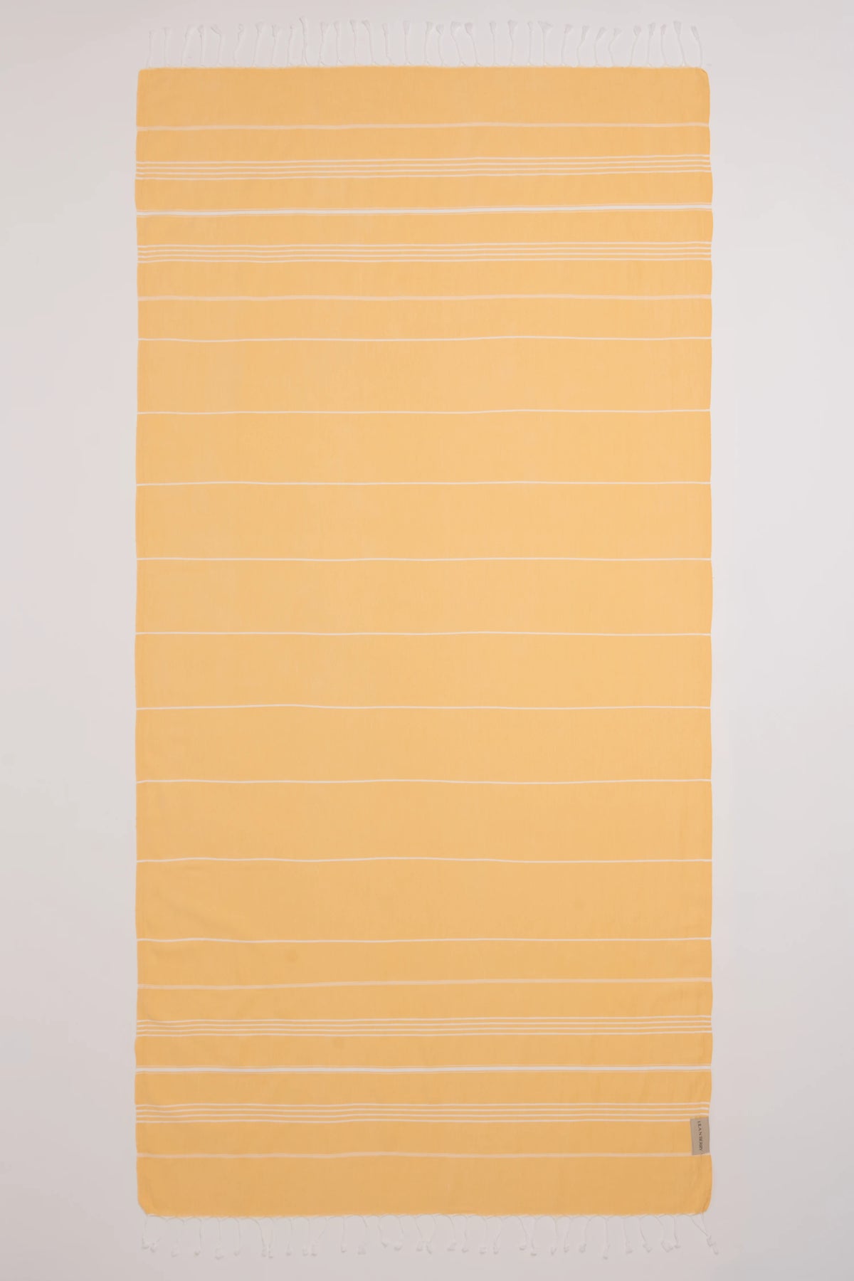 A rectangular yellow towel with thin white horizontal stripes and fringed edges, laid flat against a white background.