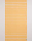 A rectangular yellow towel with thin white horizontal stripes and fringed edges, laid flat against a white background.