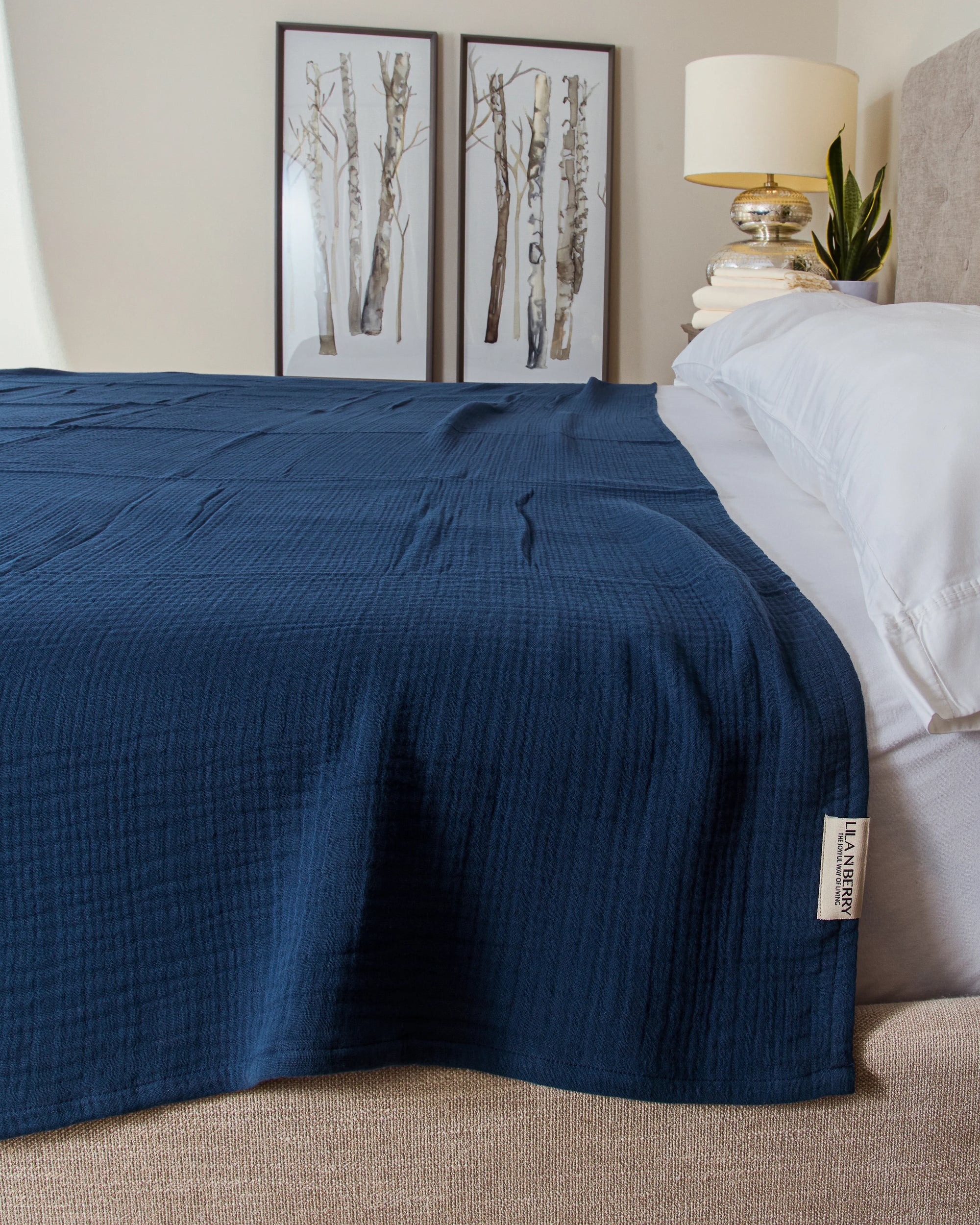 Blue textured blanket on a bed with a lamp and decor in the background