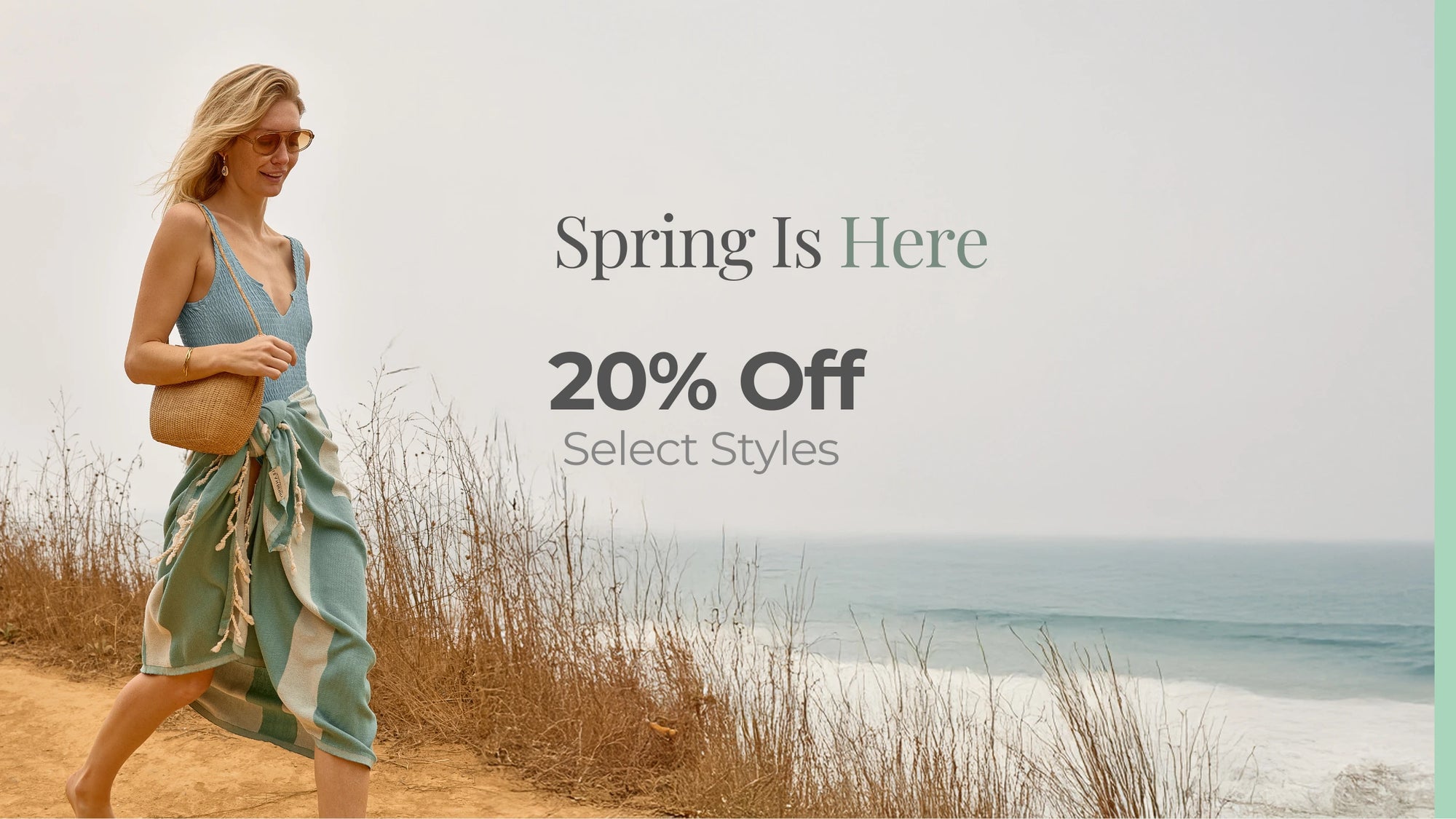 Woman walking on a beach with promotional text overlay for 20% off select styles.