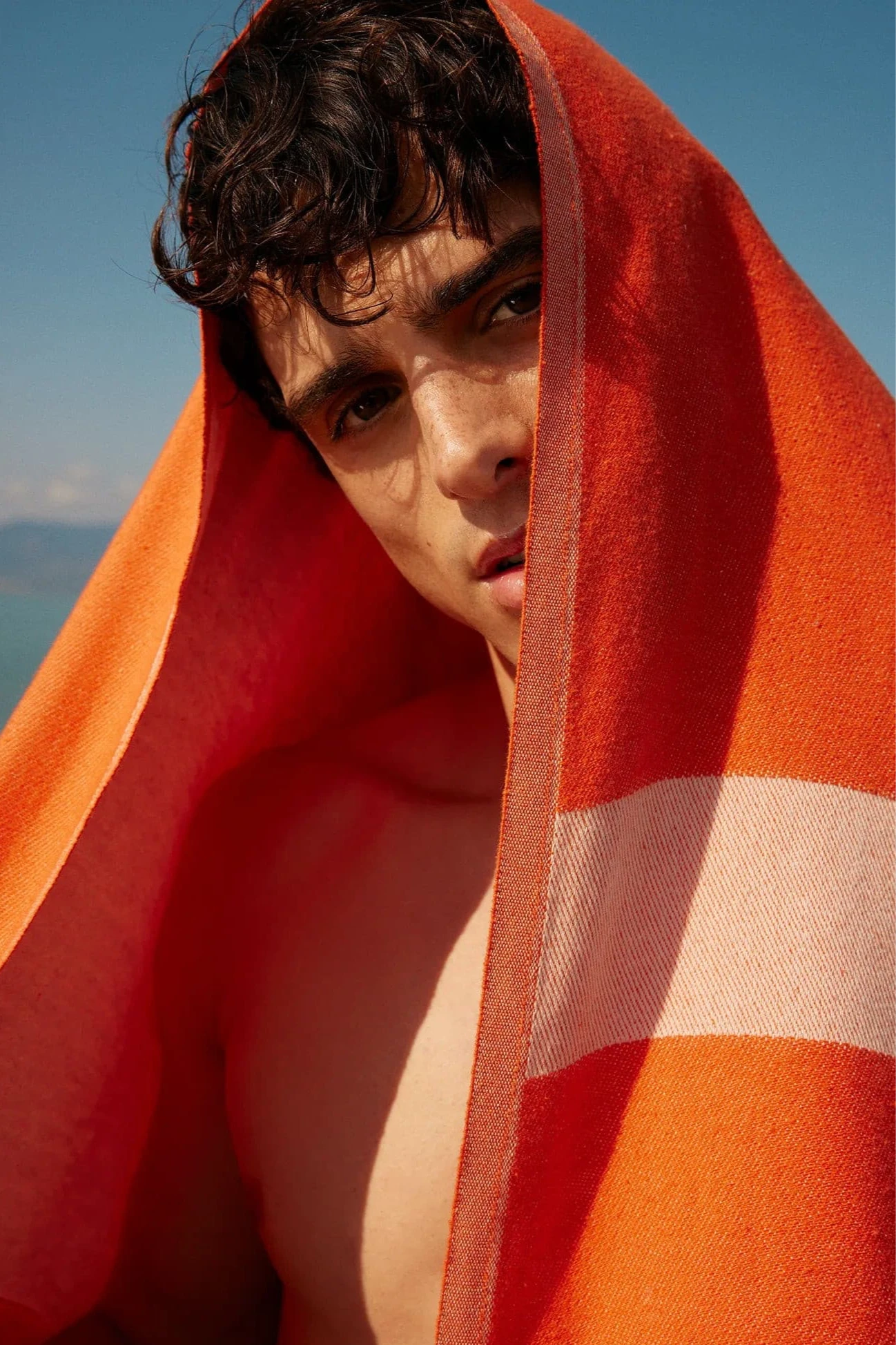 Comb Turkish towel in Sicilian Orange – draped over head with bold gaze, poolside