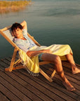 Fiori Turkish towel in Mellow Yellow – draped over lounging man on dock at lakeside, summer evening glow